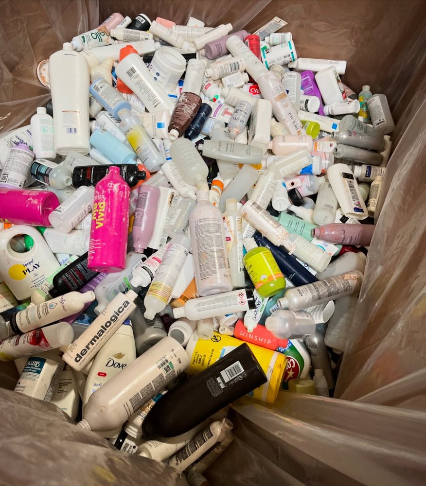 A recycling bin overflowing with empty beauty and personal care bottles